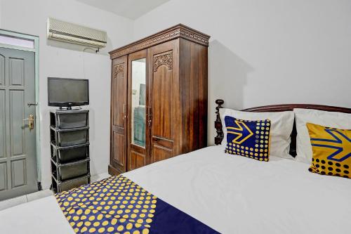 Schlafzimmer mit einem Bett, einem Holzschrank und einem TV in der Unterkunft SPOT ON 92595 Umi Homestay Syariah in Sidoarjo