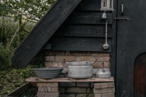 a stove with two pots and pans on a brick wall at Pipowagen de Zwerveling aan zee in Oostkapelle