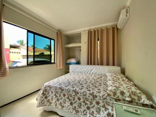 a bedroom with a bed and a large window at Flat Crystal Park Porto das Dunas in Aquiraz