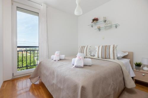 Un dormitorio blanco con una cama con dos animales de peluche. en Karlita Apartment, en Solin