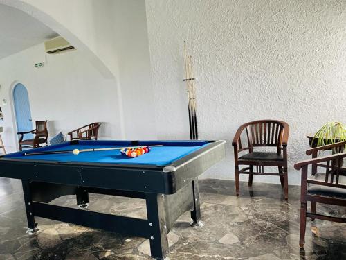una mesa de billar en una habitación con 2 sillas y una piscina en LASSION GOLDEN BAY Sea view, en Sitia
