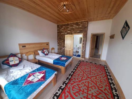 a bedroom with two beds and a red rug at Guest House Jekshen in Imeni Karla Marksa