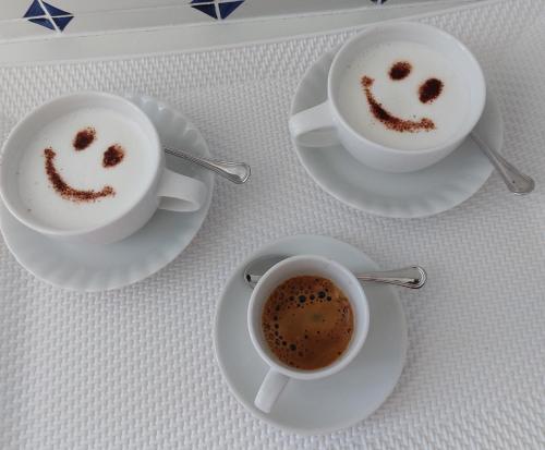 two cups of coffee with faces drawn in the coffee at B&B Il Gabbiano in Cittadella del Capo