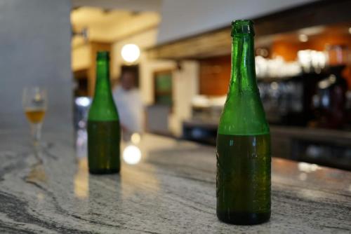 two green bottles sitting on a counter with a wine glass at Hotel Ramis fundado en 1969 in Ondara