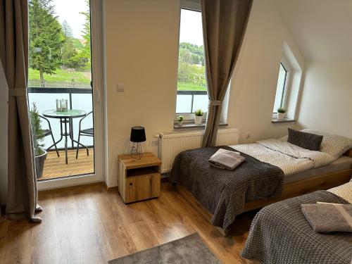 1 dormitorio con 2 camas y balcón con mesa en Domki u Edzi, en Krajno-Zagórze