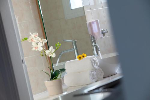 ein Bad mit einem Waschbecken, Handtüchern und einem Spiegel in der Unterkunft Princessa Vera Hotel Apartments in Paphos City