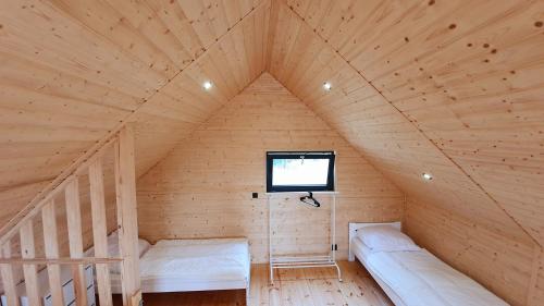 a wooden room with two beds and a window at Piaski Rogowa in Rogowo