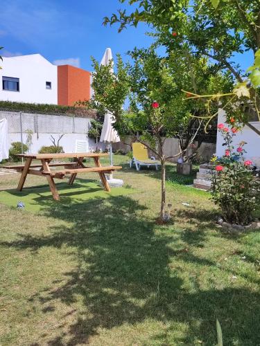 a picnic table in a yard with a tree at Apartamentos Guiomar Campos in Porto Covo