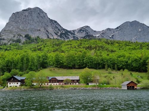 ein Haus am Ufer eines Sees mit Bergen im Hintergrund in der Unterkunft Ladner am See in Grundlsee
