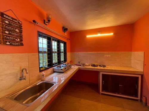 a kitchen with orange walls and a sink and a window at Mountain cheers munnar in Munnar