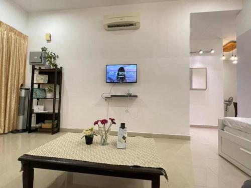 uma sala de estar com uma mesa e uma televisão na parede em Cozy 119 Homestay Teluk Intan em Teluk Intan