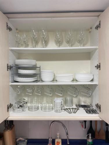 a kitchen cabinet filled with glasses and plates and a sink at Work and Rest Away From Home in Paterna