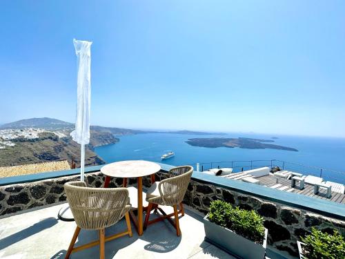 a balcony with a table and chairs and a view of the ocean at Eteoro Suites in Imerovigli