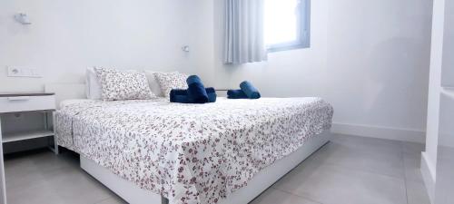 a white bedroom with a bed with blue shoes on it at Panorama Beach - Albatros Apartment in Torrox Costa