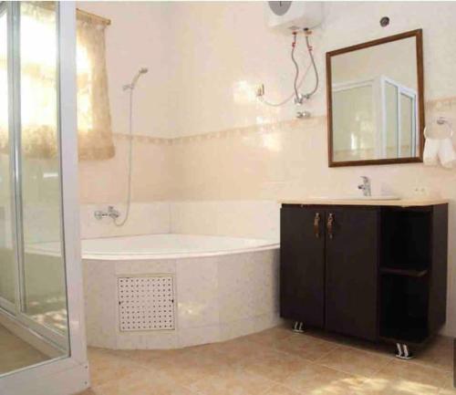 a bathroom with a tub and a sink and a mirror at JaneChill Guest House in Accra
