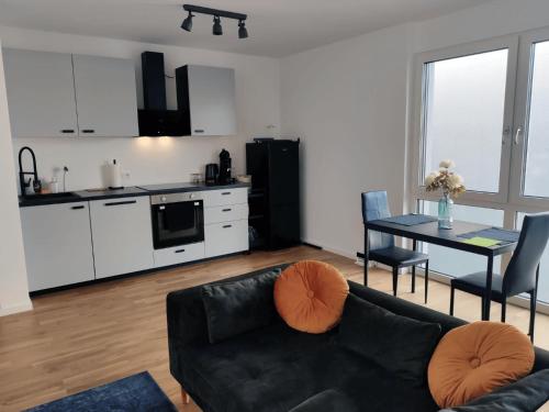 un salon avec un canapé noir et une cuisine dans l'établissement Moderne Wohnung mit Loggia - Neubau 2023, à Bergisch Gladbach