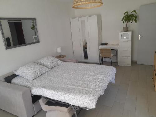 a white bedroom with a bed and a desk at F1 à 5 minutes des plages et de la gare in Vallauris
