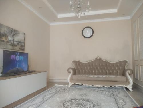 uma sala de estar com um sofá e uma televisão em Таунхаус em Bishkek