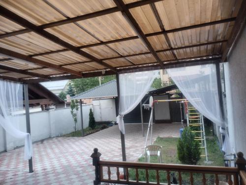 an outdoor patio with a wooden ceiling and white curtains at Таунхаус in Bishkek