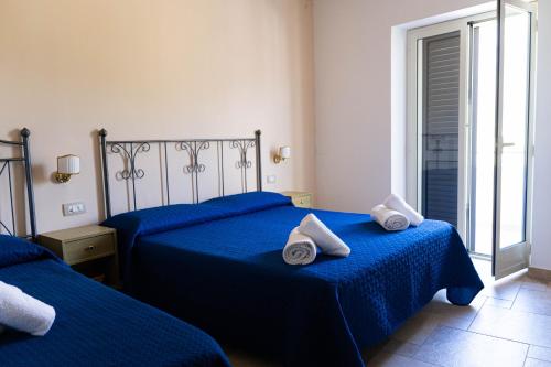 a bedroom with two beds with towels on them at Hotel Villa Senator Mediterraneo in Tortora