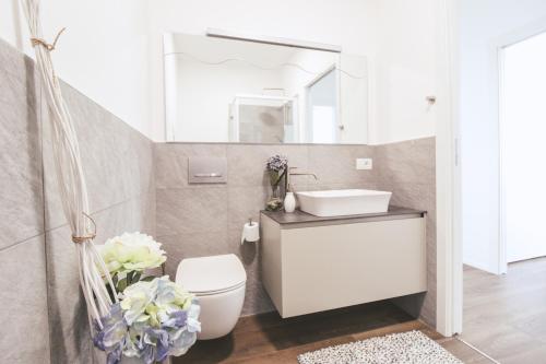 Un baño con lavabo, inodoro y espejo. en Appartamento Terrenas, en Vercana