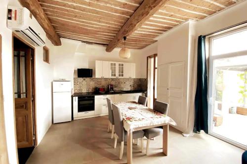 uma cozinha com uma mesa com cadeiras, uma mesa e uma janela em Appartement provençal tout confort dans le Var em Les Arcs sur Argens