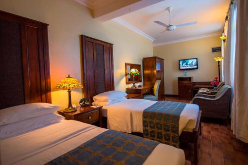 um quarto de hotel com duas camas e uma televisão em Protea Hotel by Marriott Dar es Salaam Courtyard em Dar es Salaam