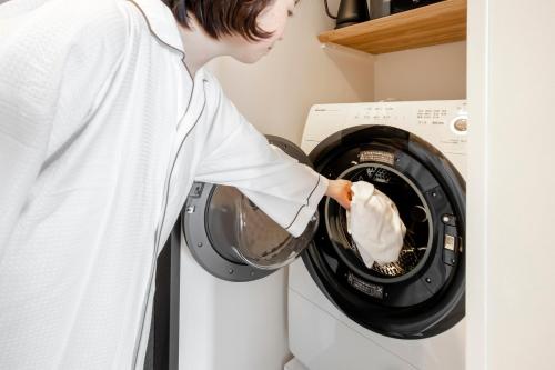 a man pouring laundry detergent into a washing machine at Tokyu Stay Hakodate Asaichi Akarinoyu in Hakodate