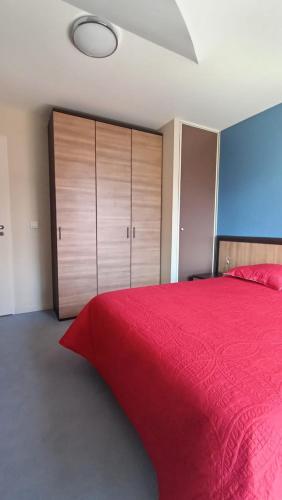 a bedroom with a red bed and wooden cabinets at Appartement Le Montagnard in Les Déserts