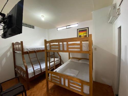 a room with three bunk beds and a television at UFO Rooms in Montañita