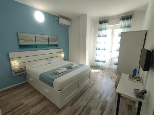 a bedroom with a white bed and a blue wall at Iris Rooms in Cagliari