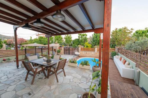 a patio with a table and chairs and a pool at Villa Filyra in Kato Gatzea