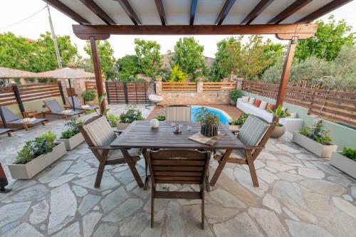 a patio with a table and chairs and a pool at Villa Filyra in Kato Gatzea