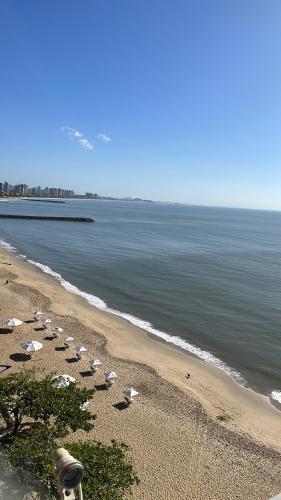 a beach with a row of umbrellas and the ocean at Frente mar in Piçarras