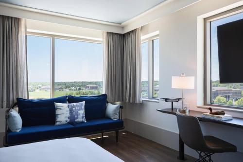 a hotel room with a blue couch and a desk and window at Renaissance Columbus Westerville-Polaris Hotel in Westerville