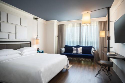 a hotel room with a bed and a blue couch at Renaissance Columbus Westerville-Polaris Hotel in Westerville
