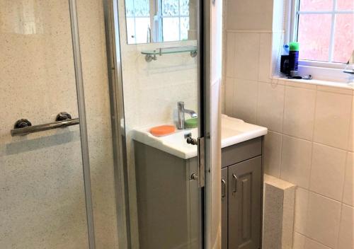 a bathroom with a shower with a sink and a shower backdoor at Glenisla in Sidmouth