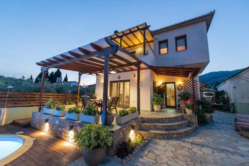 a house with a patio and a swimming pool at Villa Filyra in Kato Gatzea