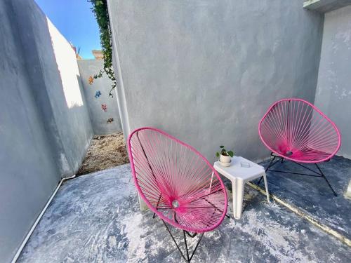 two pink chairs and a table on a patio at Cozy apartment king bed ac downtown in Cozumel
