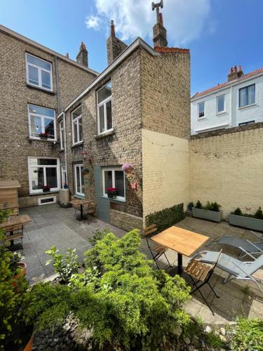 un patio con una mesa de madera frente a un edificio en Villa Artiz, en Dunkerque