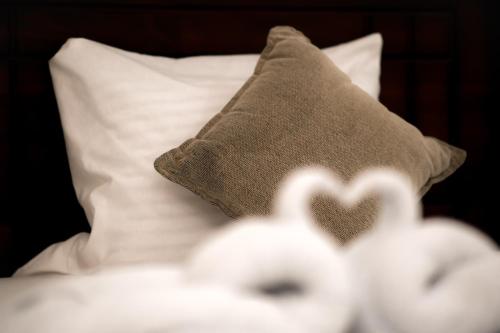 a heart pillow on a bed with white pillows at White Win Villa in Elewala