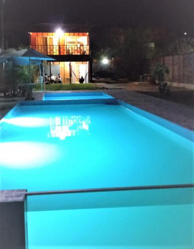 a blue pool with a house in the background at night at Hospedaje & Casa Playa AURORA in Zorritos