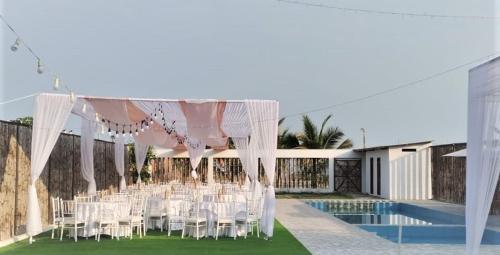 a marquee with white chairs and a pool at Hospedaje & Casa Playa AURORA in Zorritos