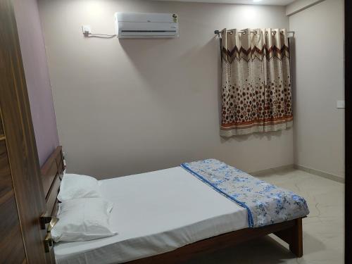 a small bedroom with a bed and a curtain at Manasvi in Mangalore