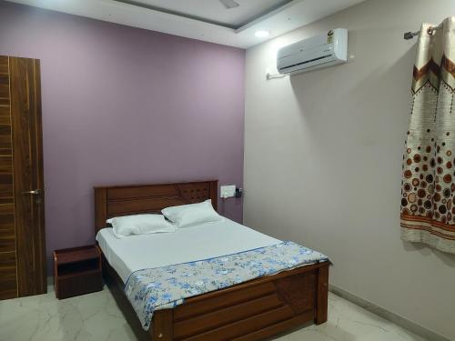 1 dormitorio con 1 cama en una pared blanca en Manasvi en Mangalore