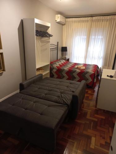 a bedroom with a bed and a couch in it at Studioaconchegantepoa in Porto Alegre