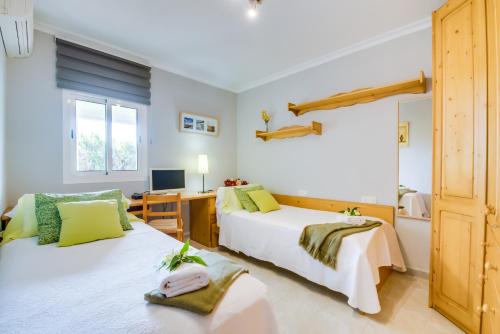a bedroom with two beds and a desk and a television at Finca Alegre in Lloseta