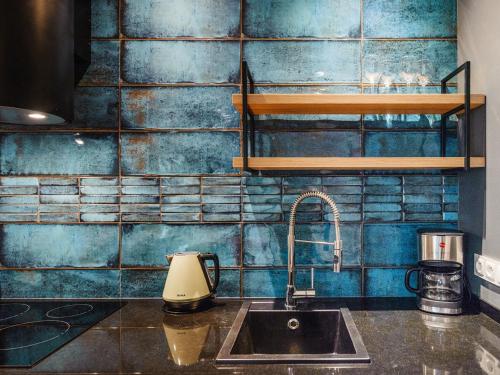 ソポトにあるSo Harmony luksus przestrzeń i parkingの青いタイル張りの壁、シンク付きのキッチンが備わります。