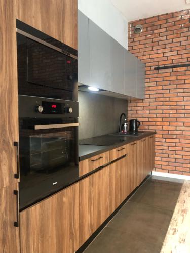 a kitchen with black appliances and a brick wall at Manufaktura Apartamenty BakeryHouse PRYWATNA KAMIENICA PARKING STRZEŻONY KLIMA DOSTEP NA KOD in Łódź