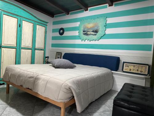 a bedroom with a bed and blue and white stripes at Appartamento Picasso in Cala Gonone